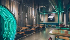 Un restaurant moderne doté d’un espace salon aux lignes courbes, de chaises suspendues et d’une grande fresque murale.