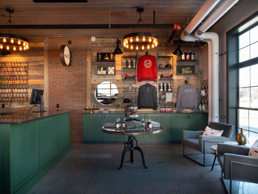 Zona de bar moderna con pared de ladrillo, estantes de madera y una mesa redonda con un reloj.