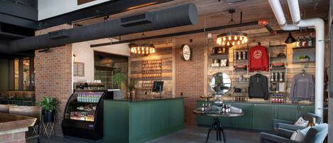 A bar area with a green counter, a seating area with a sofa and chairs, and a display of bottles and glasses.
