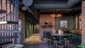 Una zona de bar con taburetes, pared de ladrillo y chimenea.