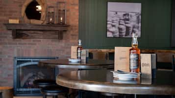 A restaurant interior with a brick fireplace, round tables, and stools.
