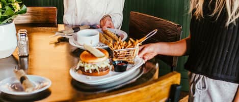 A dining table with a burger, fries, and a cup.