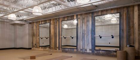 A spacious room with large mirrors, exercise mats, and a ceiling with exposed ductwork.