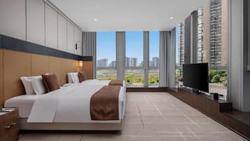 A hotel room with a large bed, a TV, and a view of high-rise buildings.