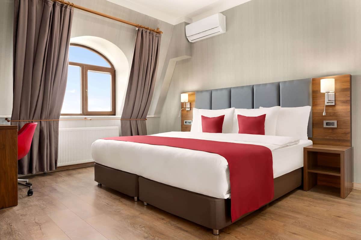 A modern hotel room with a large bed, a desk, and a chair.