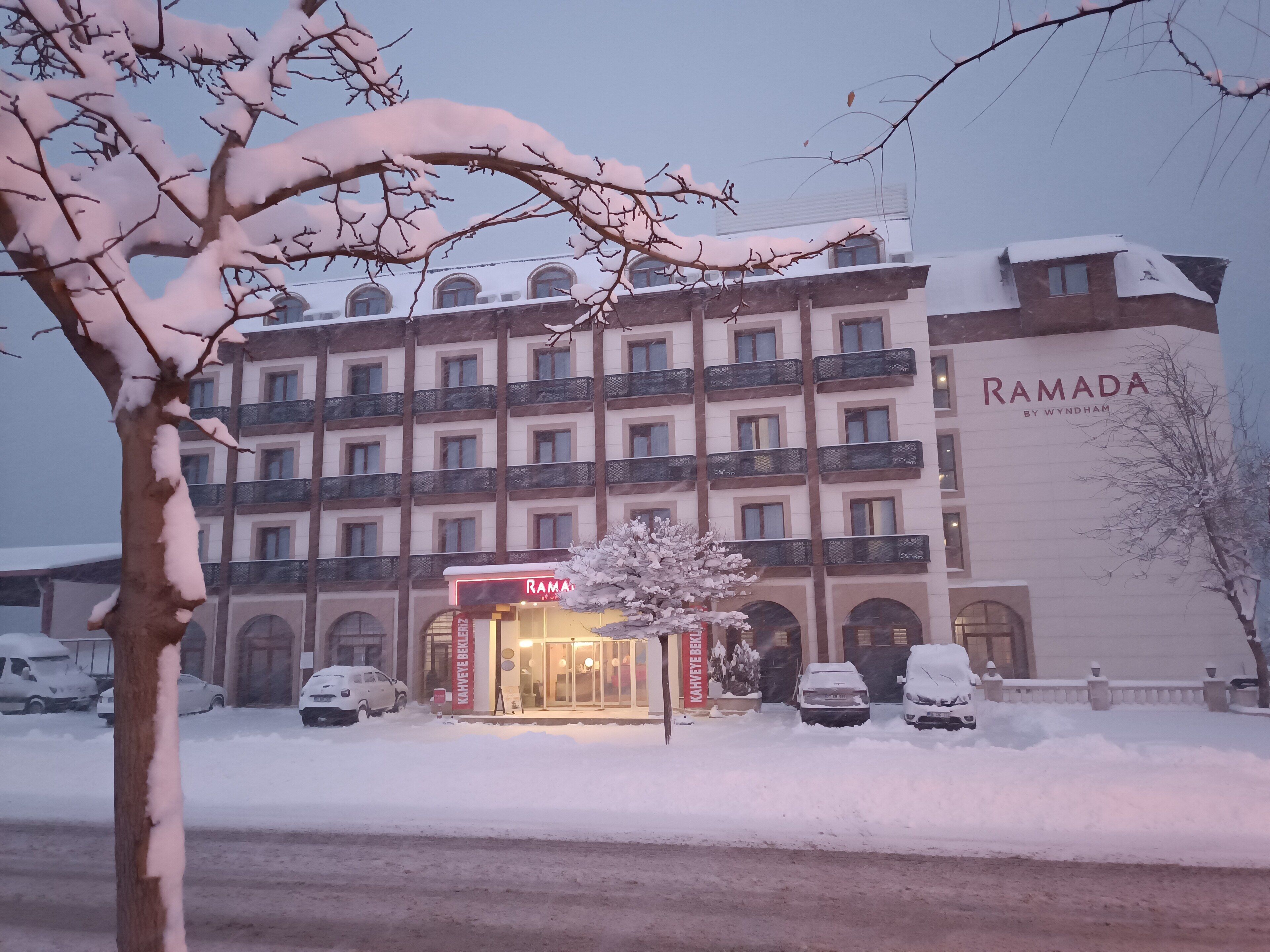 A multi-story hotel with a prominent "RAMADA" sign, featuring a traditional architectural style with balconies and arched windows.
