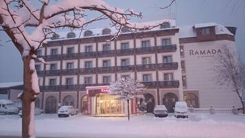 A multi-story hotel with a prominent "RAMADA" sign, featuring a traditional architectural style with balconies and arched windows.
