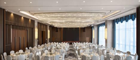 A large conference room with round tables and chairs, a patterned carpet, and a chandelier.