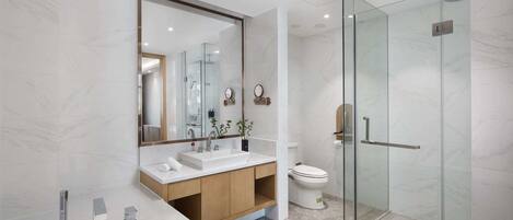 A modern bathroom with a glass shower enclosure, a large mirror, and a white sink.