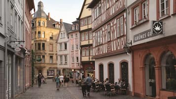 Eine Kopfsteinpflasterstraße, gesäumt von traditionellen europäischen Gebäuden, von denen einige Schilder zeigen.