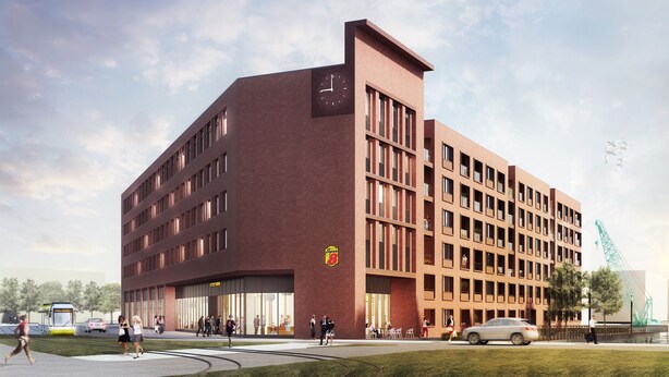 Un bâtiment moderne doté d’un imposant clocher, de grandes fenêtres et d’un espace d’entrée bien visible, où l’on peut apercevoir des personnes et des voitures.