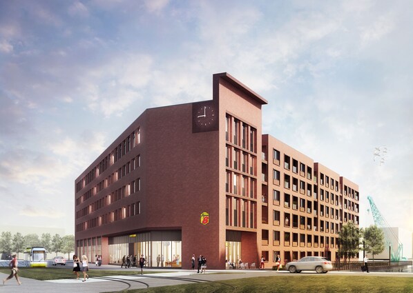 Een modern gebouw met een opvallende klokkentoren, grote ramen en een goed zichtbaar entreegebied met mensen en auto's.