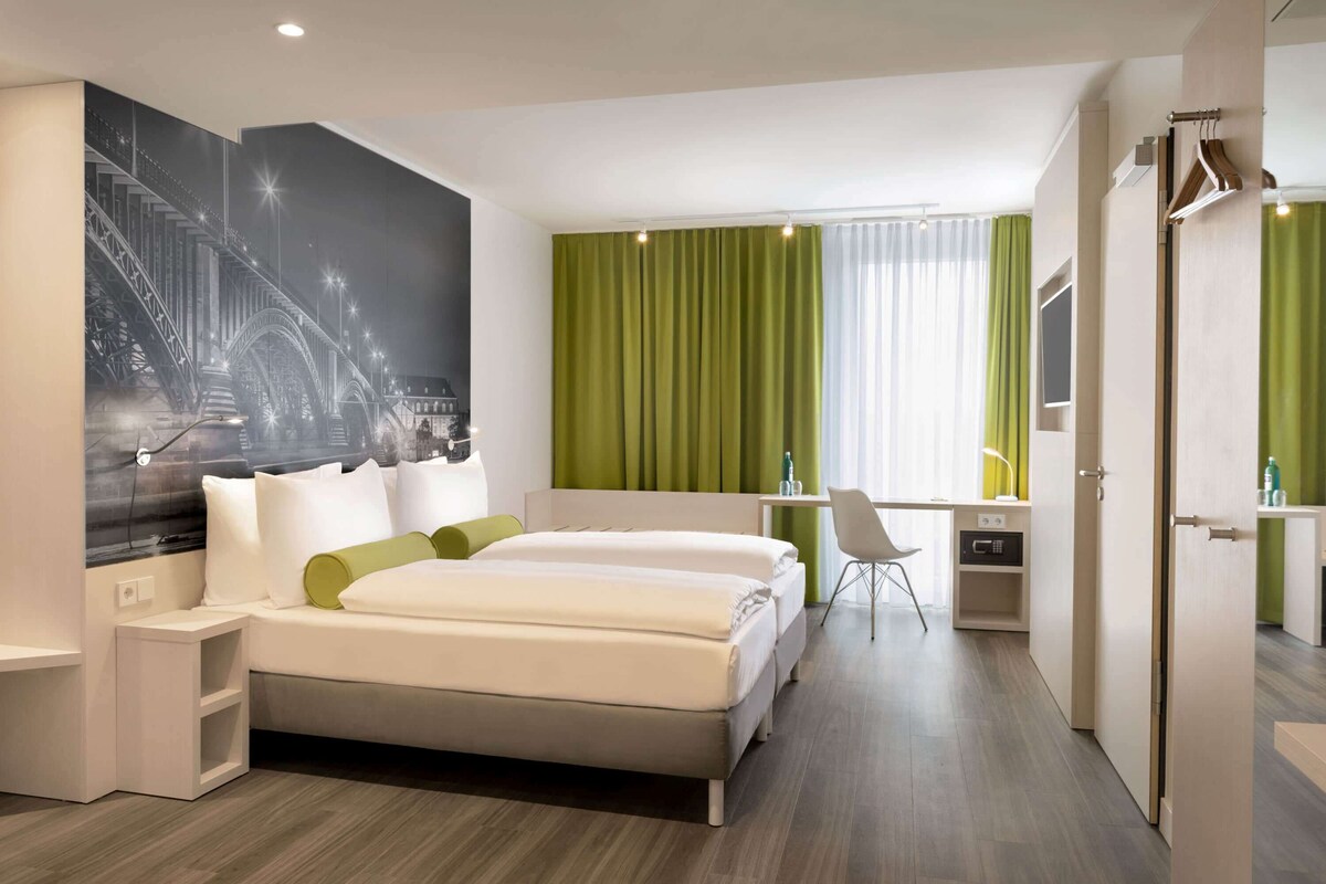 Ein modernes Hotelzimmer mit einem großen Bett, einem Schreibtisch und einem Stuhl.