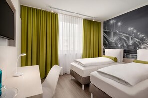A hotel room with two beds, a desk, a chair, a TV, and a large window with curtains.