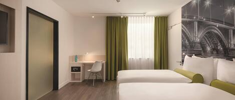 Habitación de hotel con cama, escritorio, silla y un ventanal con cortinas.