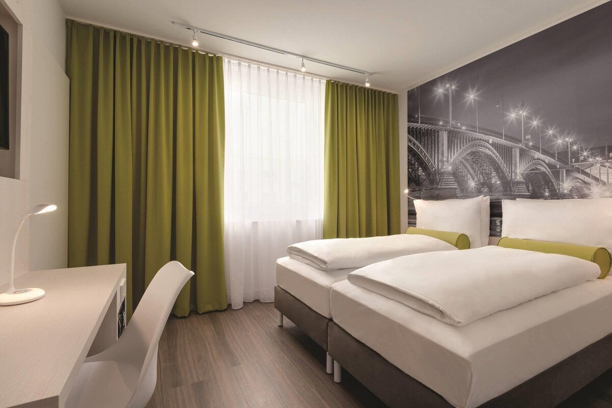 Een hotelkamer met twee bedden, een bureau en een stoel.