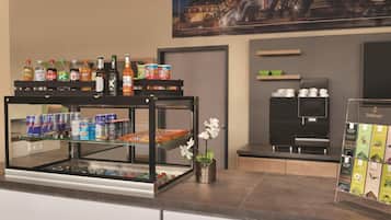 Un área de bar con diversas bebidas y aperitivos, una vista urbana enmarcada y una exhibición de cajas de té.