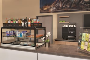 Un espace bar proposant une variété de boissons et d’en-cas, une vue sur la ville encadrée et une présentation de boîtes à thé.