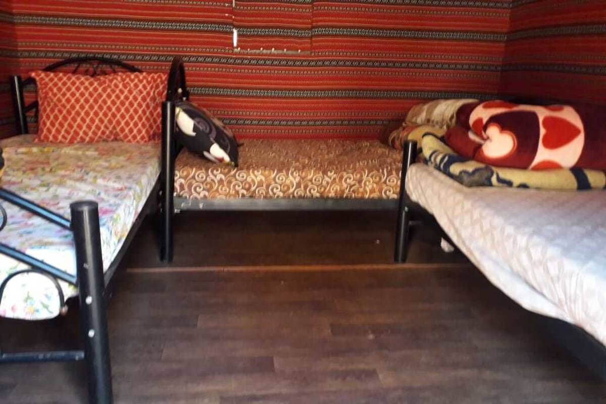 A room with two single beds, a patterned rug, and a wooden floor.