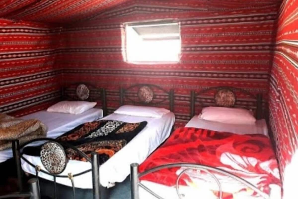 A room with two beds, a small window, and patterned walls.