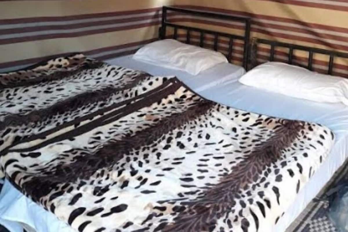 A single bed with a striped wall and a window.