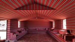 Una habitación con paredes y techo a rayas, piso alfombrado y un banco a lo largo de una pared.