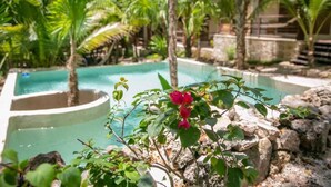 A swimming pool surrounded by tropical vegetation and stone walls. - Hotel Buenavista Bacalar Jungle Experience (Bacalar)