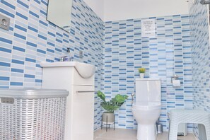 A bathroom with a white sink, toilet, and a trash bin.