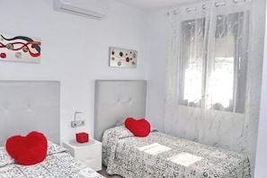 A bedroom with two beds, a nightstand, a wall-mounted air conditioner, and a window with a curtain. - Fabulous holiday home with private pool (Conil de la Frontera)