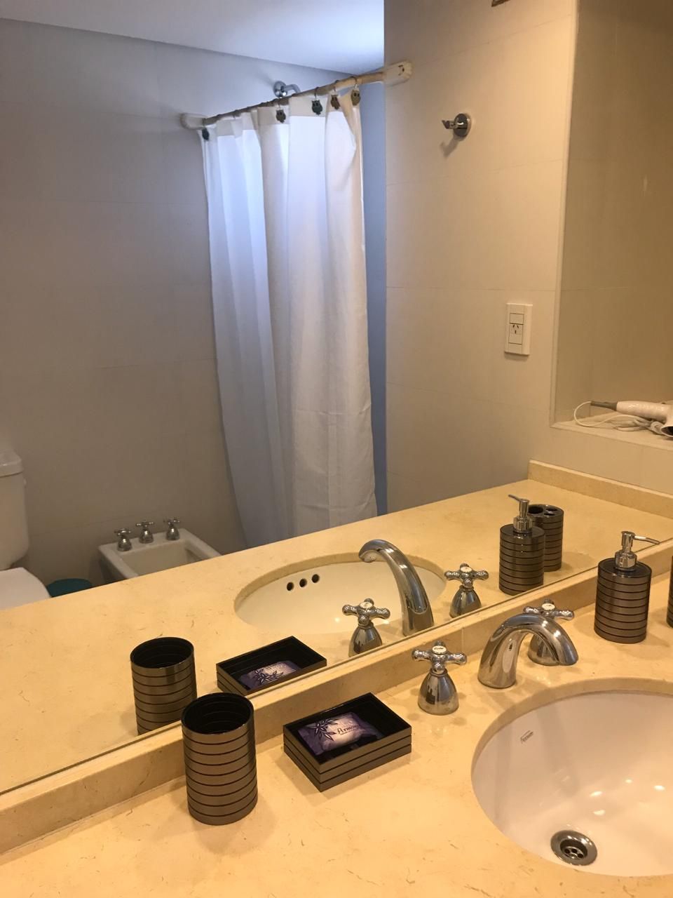 A bathroom with a sink, mirror, and shower curtain.