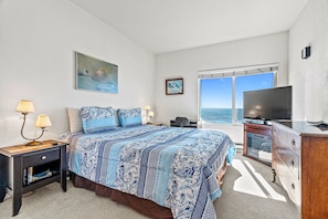 A bedroom with a large bed, a TV, a dresser, and a window with a view of the ocean. - Two Bedroom Condo With Great Ocean Views! (Aptos)