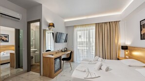 Habitación de hotel con una cama grande, un escritorio con computadora, televisor y zona de ducha.
