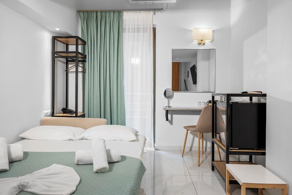 Una habitación de hotel moderna con una cama, un escritorio con silla, un televisor y un espejo.