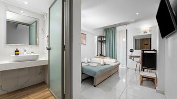 Une chambre d’hôtel moderne, dotée d’un grand lit, d’une table de chevet, d’une télévision et d’une salle de bain avec un lavabo et un miroir.