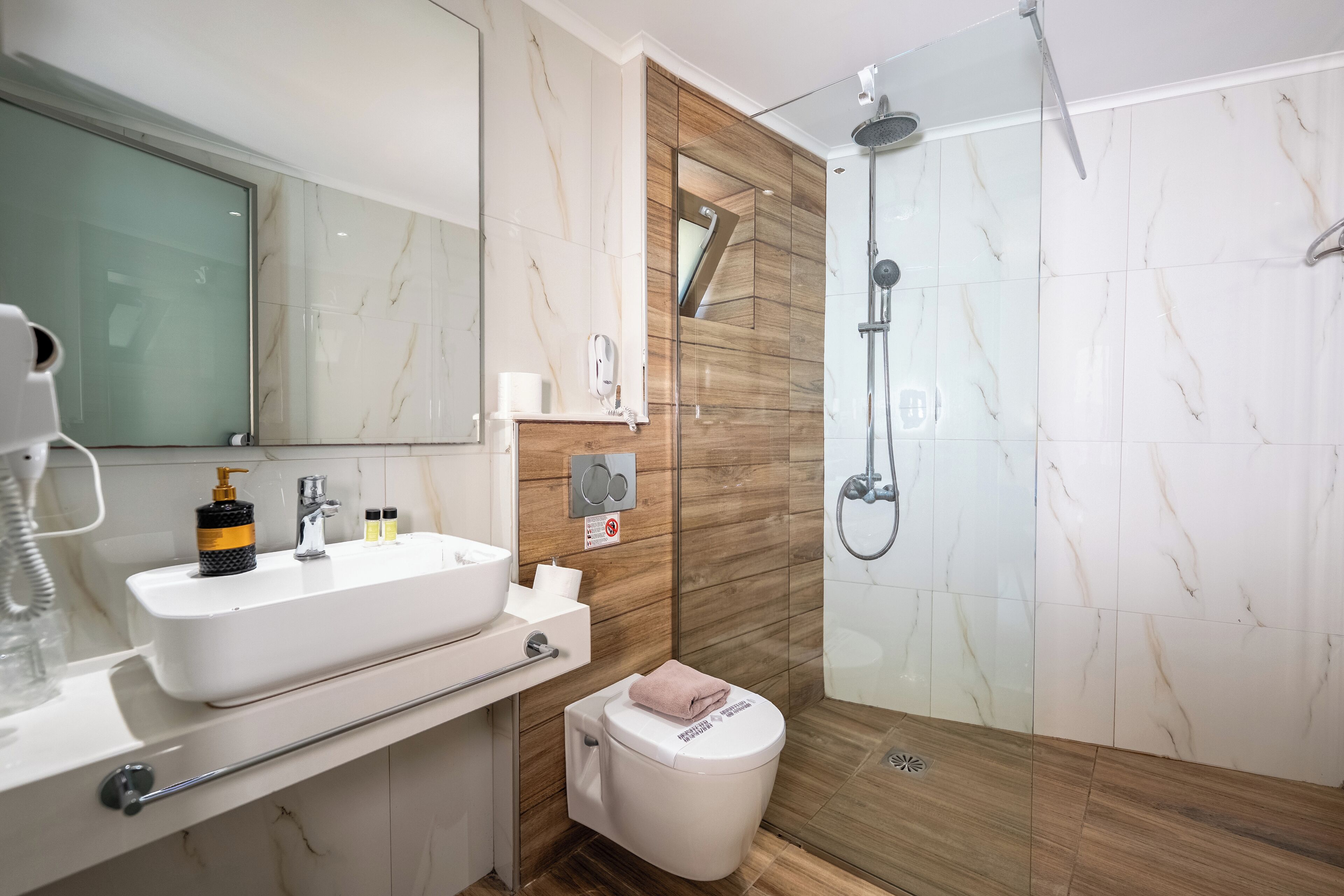 A modern bathroom with a white sink, mirror, and shower.