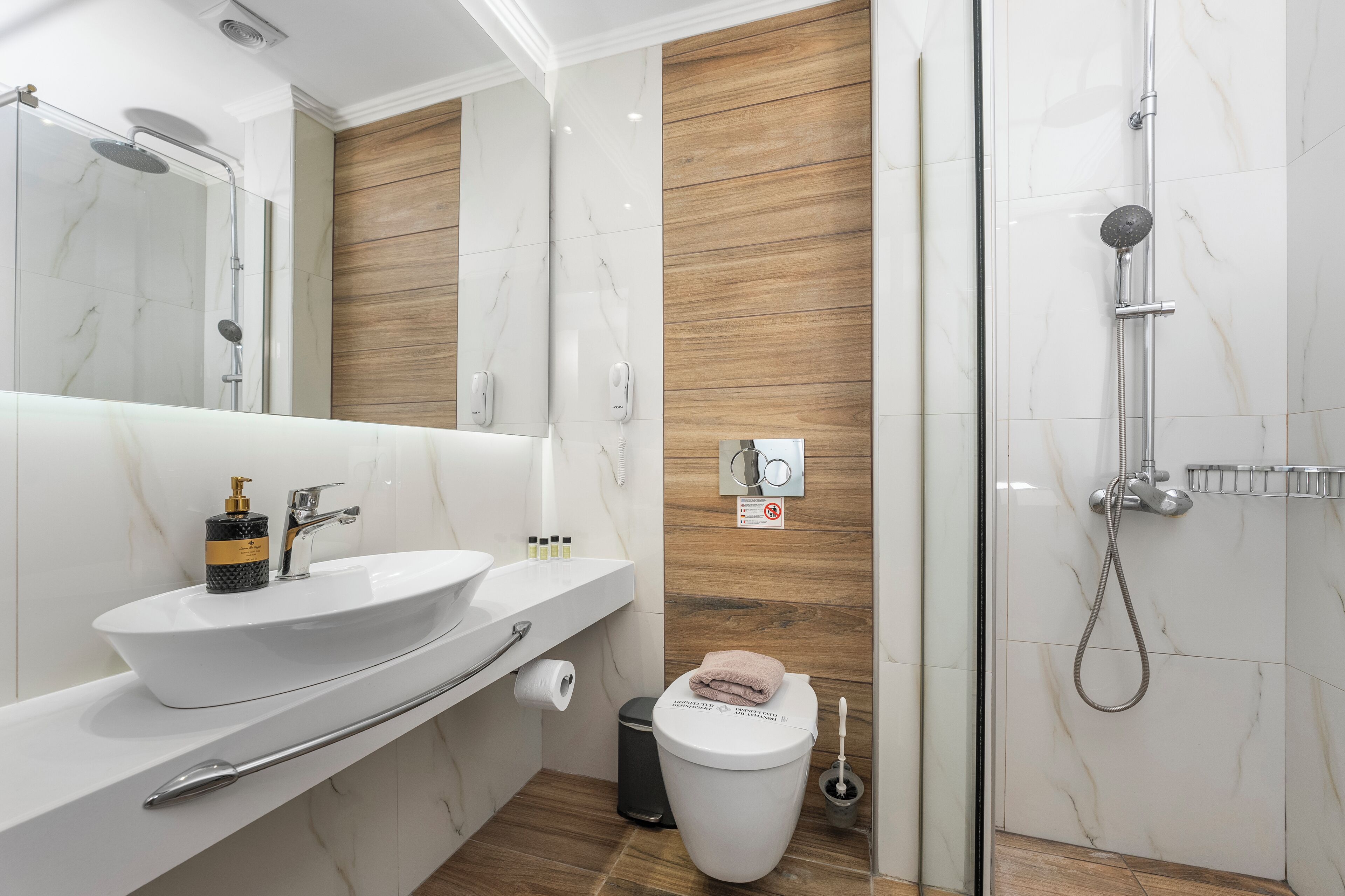 A modern bathroom with a white sink, mirror, and shower.