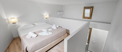 Ein modernes Hotelzimmer mit einem Bett, Nachttischlampen, einem Spiegel und Holzboden.