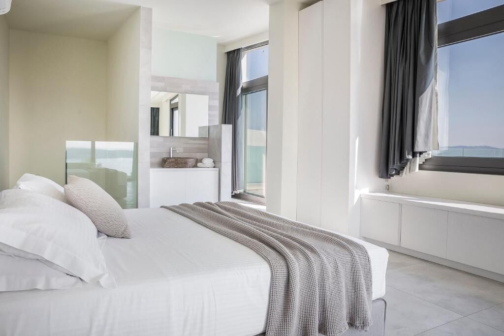 A modern bedroom with a large bed, a view of the city, and a window with curtains.