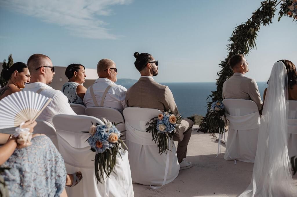 Une cérémonie de mariage où les invités sont assis face à l’autel, avec une vue panoramique en toile de fond.