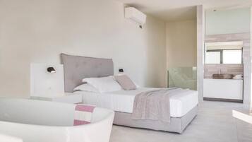 A modern bedroom with a bed, bedside tables, a glass shower enclosure, and a white bathtub.