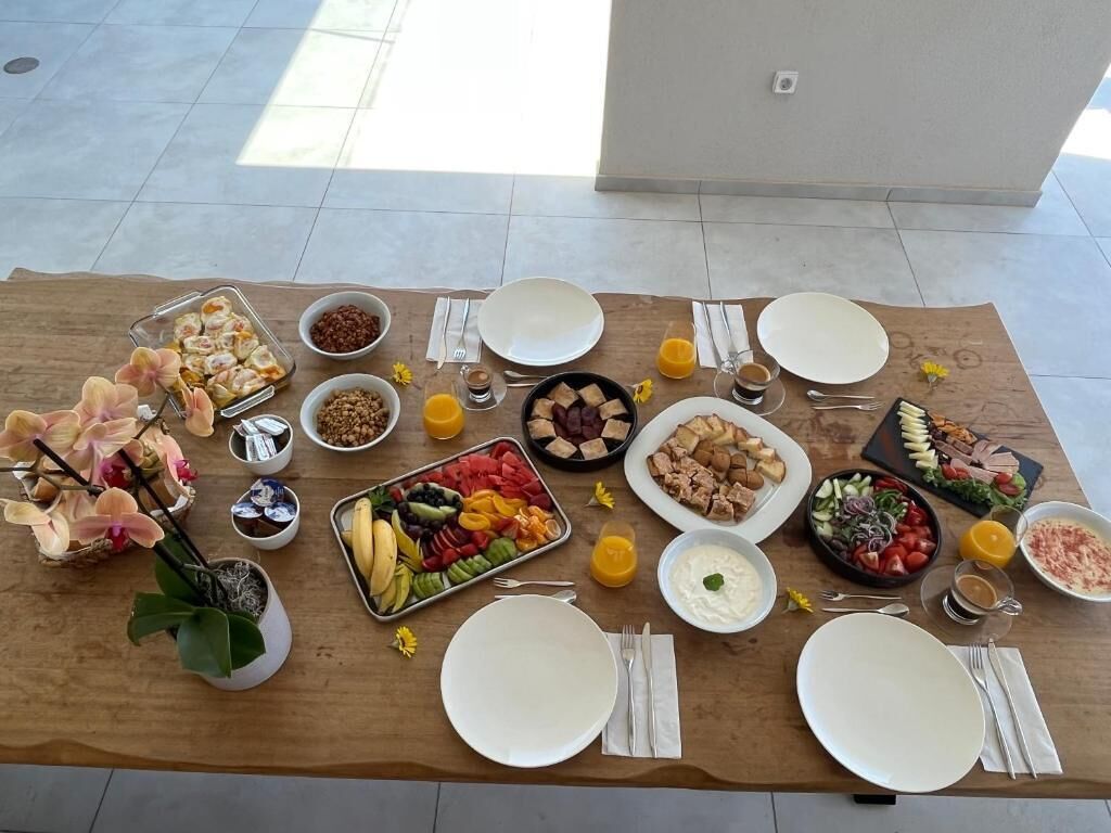 Un bufé de desayuno con diversos alimentos y bebidas sobre una mesa de madera en una habitación luminosa.