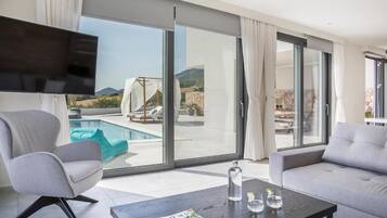 Una sala de estar moderna con vista a la piscina, un televisor de pantalla plana y un sofá.