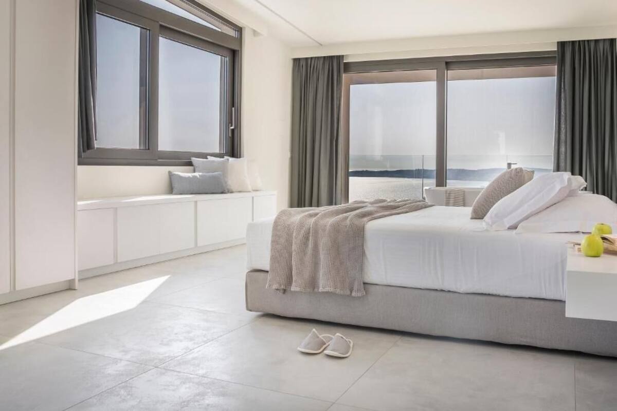 Habitació d'hotel moderna amb un llit gran, vistes a la ciutat i una finestra amb cortines.