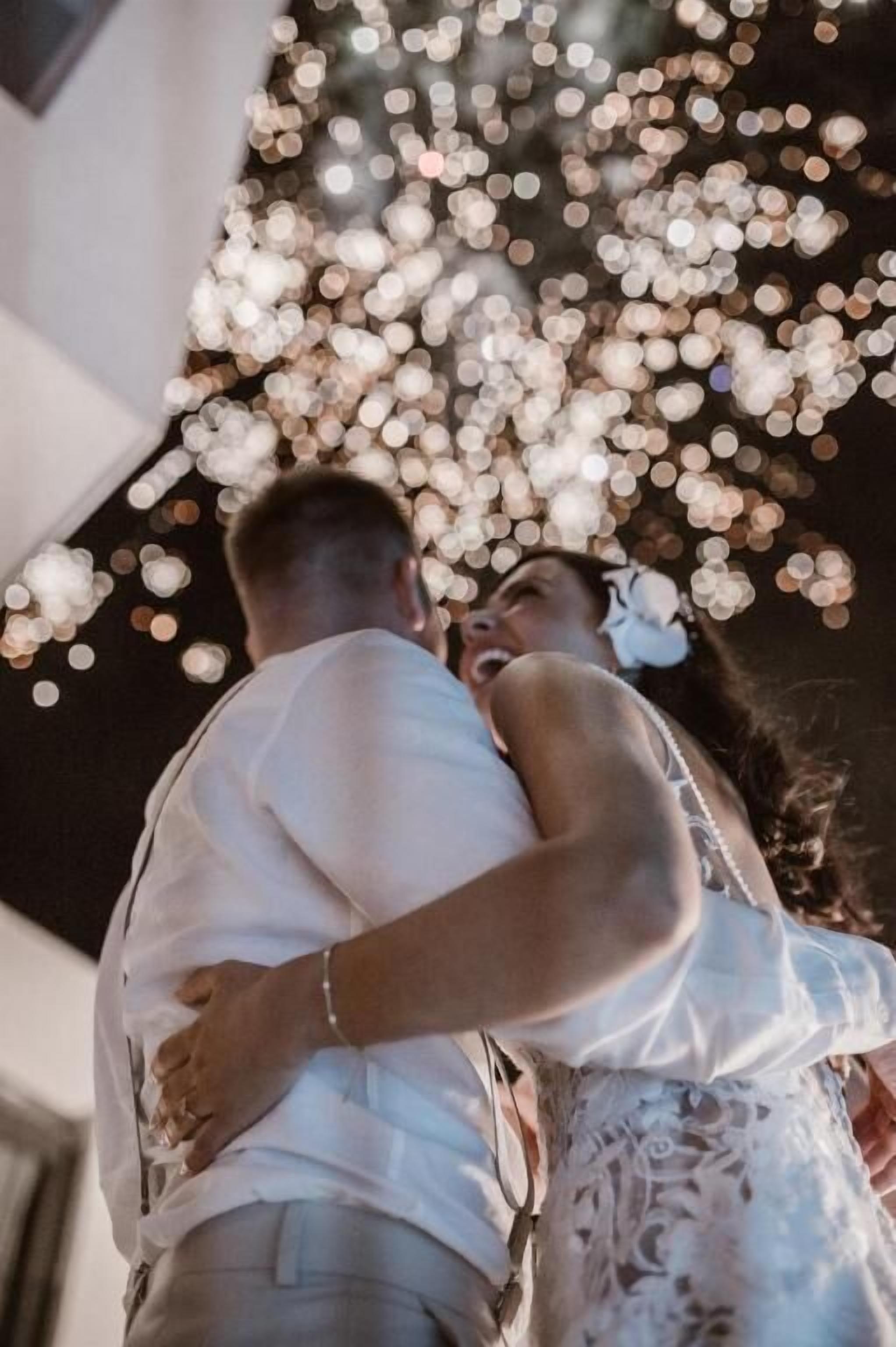 Una pareja abrazándose bajo una guirnalda de luces.