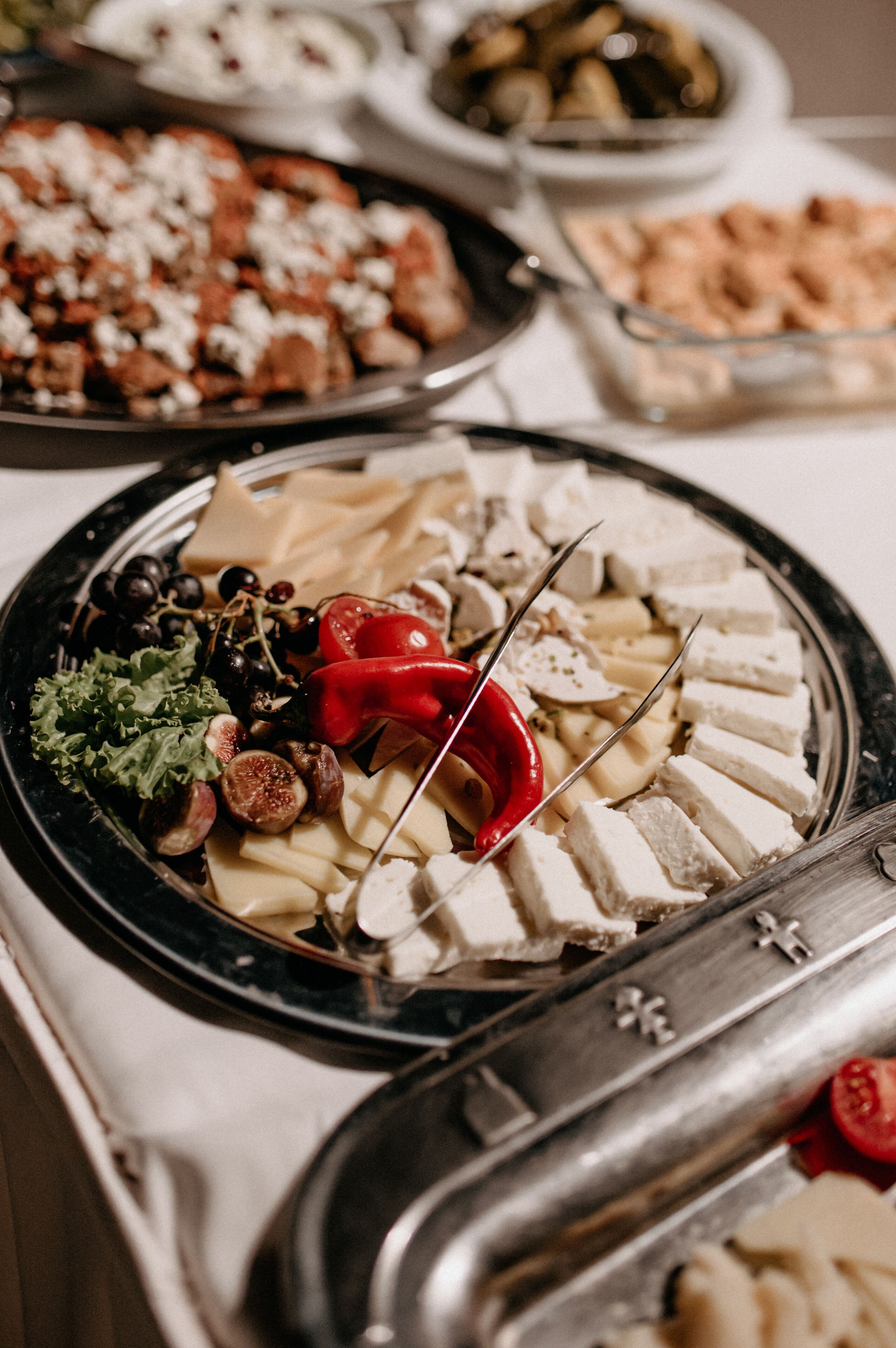 A buffet with various cheeses, fruits, and vegetables.