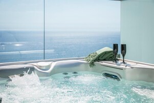 Un jacuzzi con vistas al océano, una toalla y dos vasos.