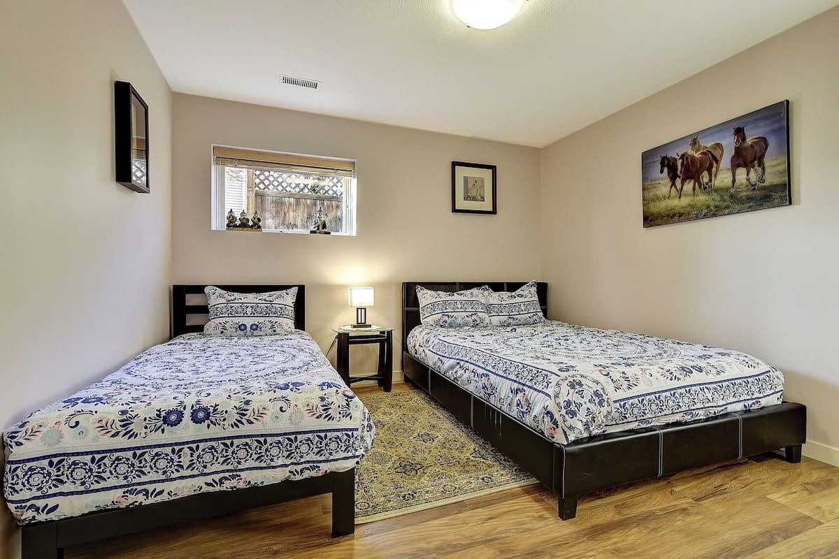 Une chambre avec deux lits, une fenêtre, une lampe et un tableau au mur.