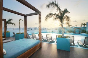 Ein Hotelzimmer mit Bett, einem Poolbereich mit Liegestühlen und Palmen.