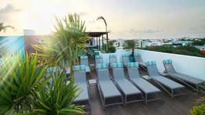 A rooftop lounge area with sun loungers and a view of the cityscape. - The Gallery Apartments (Playa del Carmen)