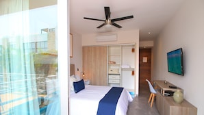 A modern hotel room with a bed, a desk, a chair, a wardrobe, and a ceiling fan. - The Gallery Apartments (Playa del Carmen)